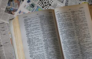 diccionario de inglés abierto sobre fondo de hojas escritas.